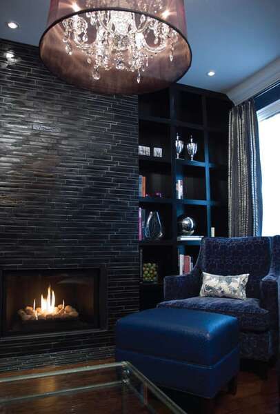 Современный камин в гостиной, чёрный стеллаж, синее кресло и пуфик