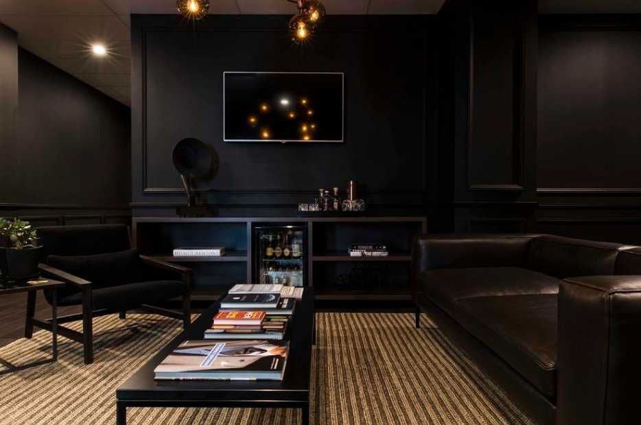 Коричневый пол в чёрной гостиной, чёрный диван и журнальный столик