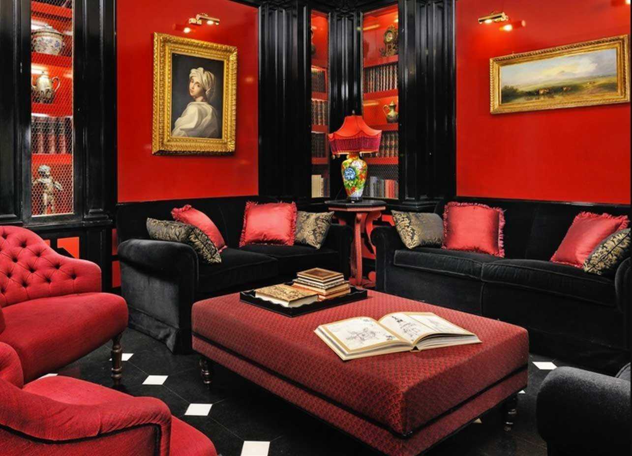 Чёрно-красный интерьер английской гостиной, красный пуфик и чёрные диваны