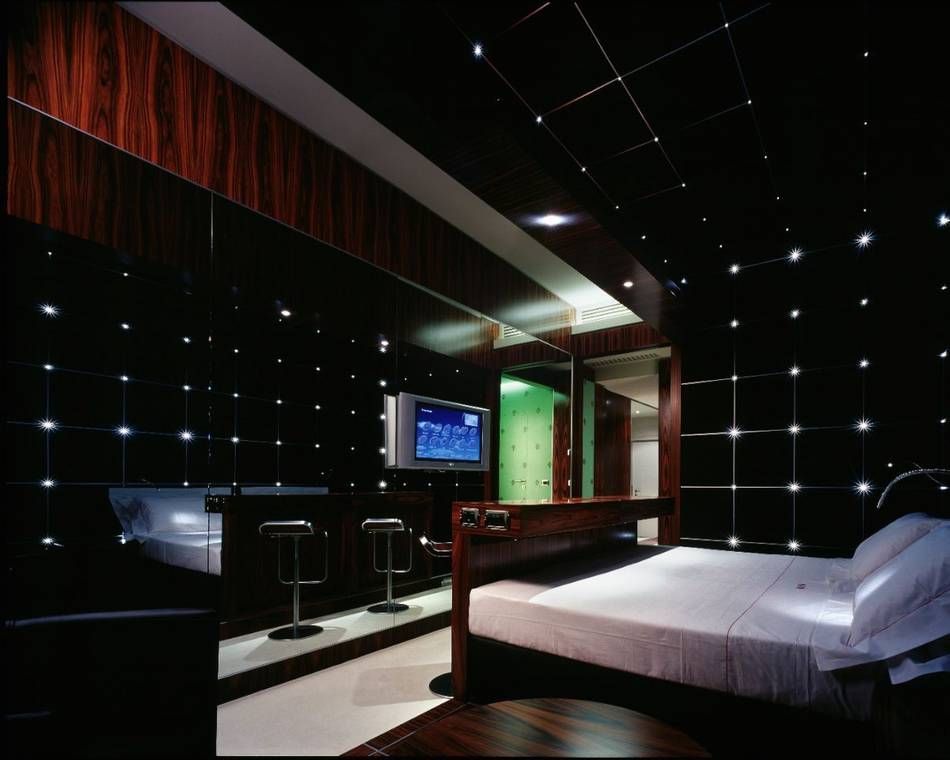 Чёрный интерьер спальни, номер в отеле, стены тёмные стеклянные панели с подсветкой